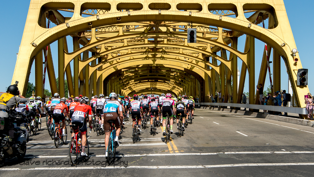 Riders pass under the historic Tower Bridge as they head out during the neutralized start of Men's Stage Seven, Sacramento, 2018 Amgen Tour of California cycling race (Photo by Dave Richards, daverphoto.com)
