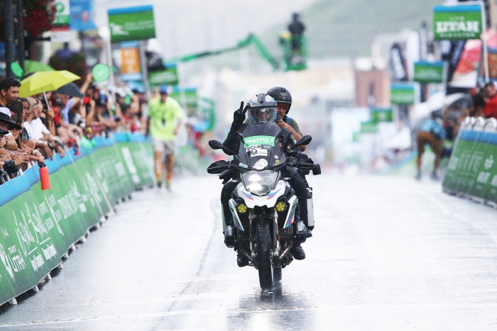 Photo moto Jimmy Faria and photographer Brian Hodes rides to the Finish in an epic rain storm.  2018 Tour of Utah Stage 6, August 12, 2018, Park City, Utah. Photo by Cathy Fegan-Kim, cottonsoxphotography.net