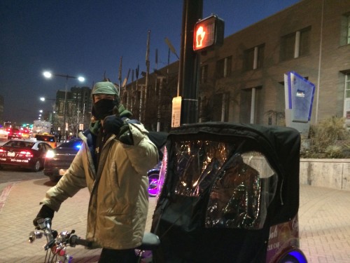A pedicab driver stays warm in winter. Photo by Dave Iltis
